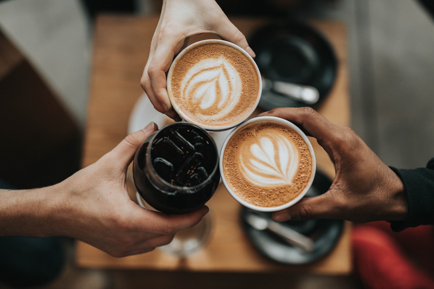 Three cups of coffee raised together over a café table.
