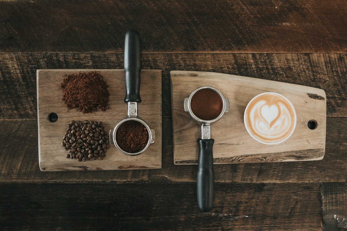 A flat-lay of a portafilter, fresh grounds and whole beans on warm wood.