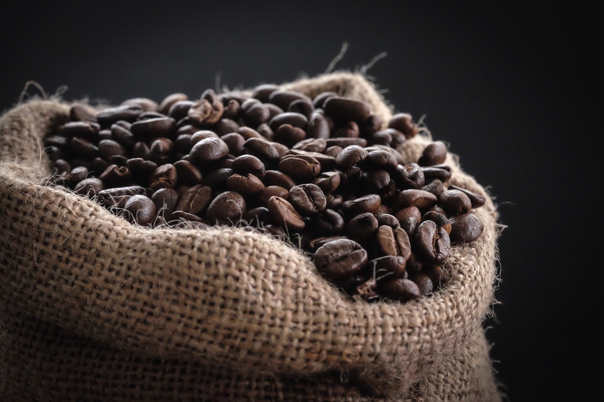 A burlap sack brimming with whole coffee beans.